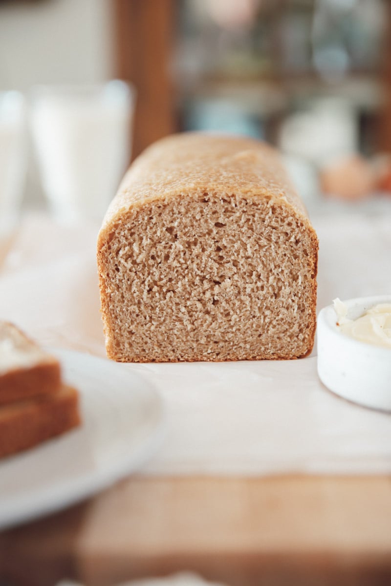 Close-up of sliced whole wheat sourdough sandwich bread showing soft, tight crumb and golden color.