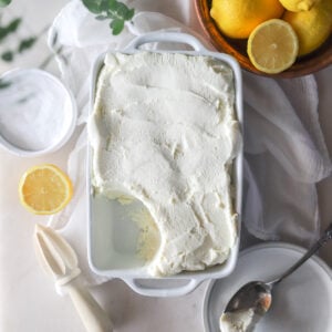 Top view of homemade cream cheese in a white dish with lemons around it.