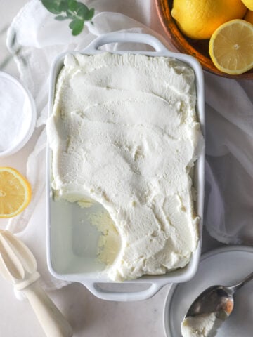 Top view of homemade cream cheese in a white dish with lemons around it.