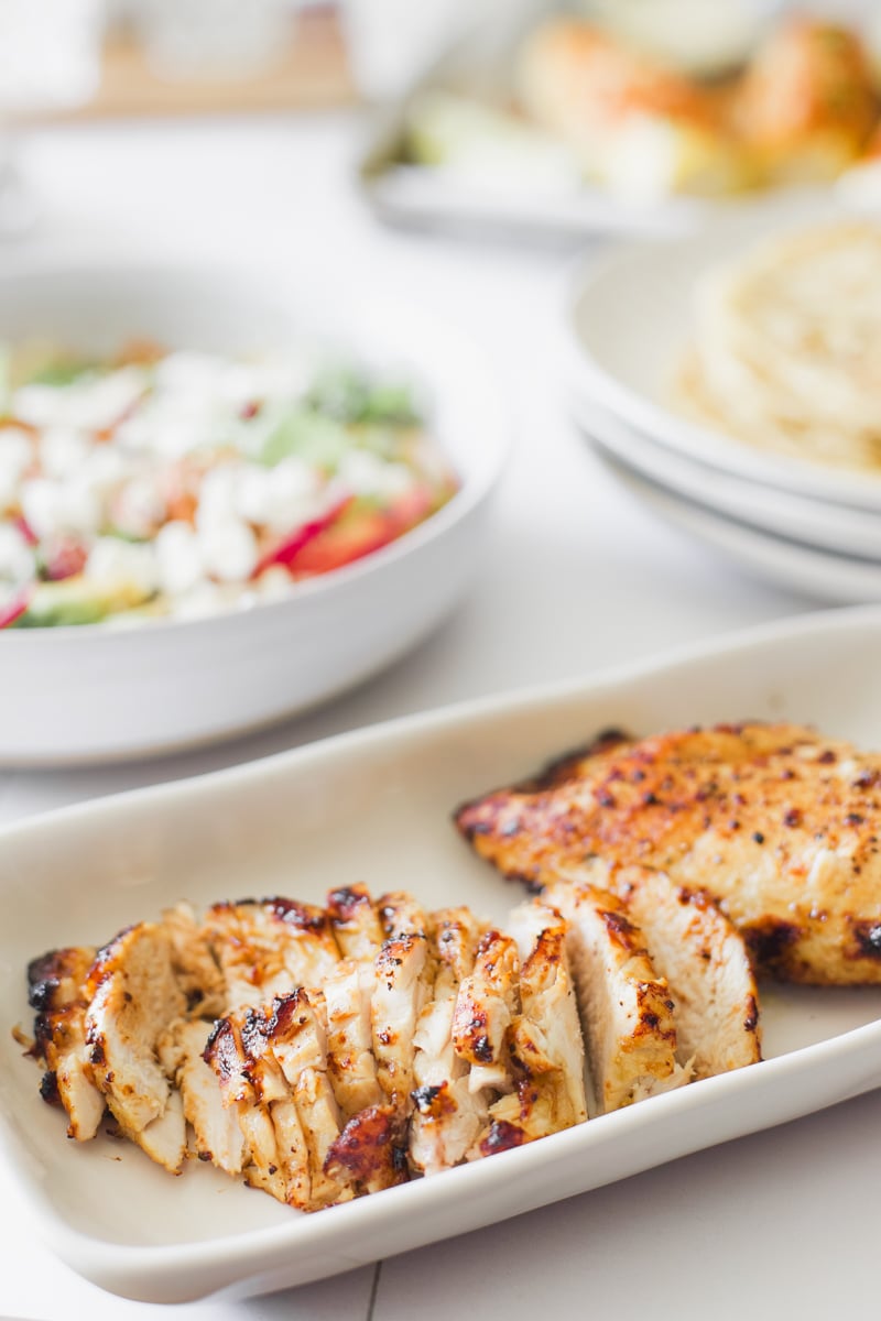 Sliced air fryer chicken breast served with harvest chicken salad ingredients in the background.