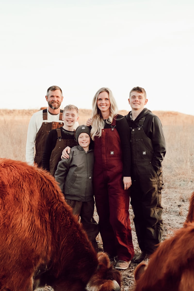 The Austin Family posed for a photo with their family milk cow herd in a winter pasture wearing berne coveralls.
