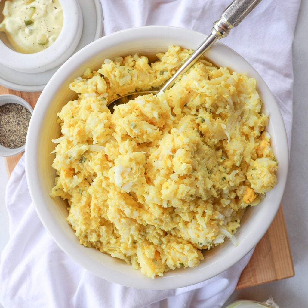Square overhead photo of old-fashioned German potato salad made with shredded potatoes, eggs, and creamy mustard dressing.