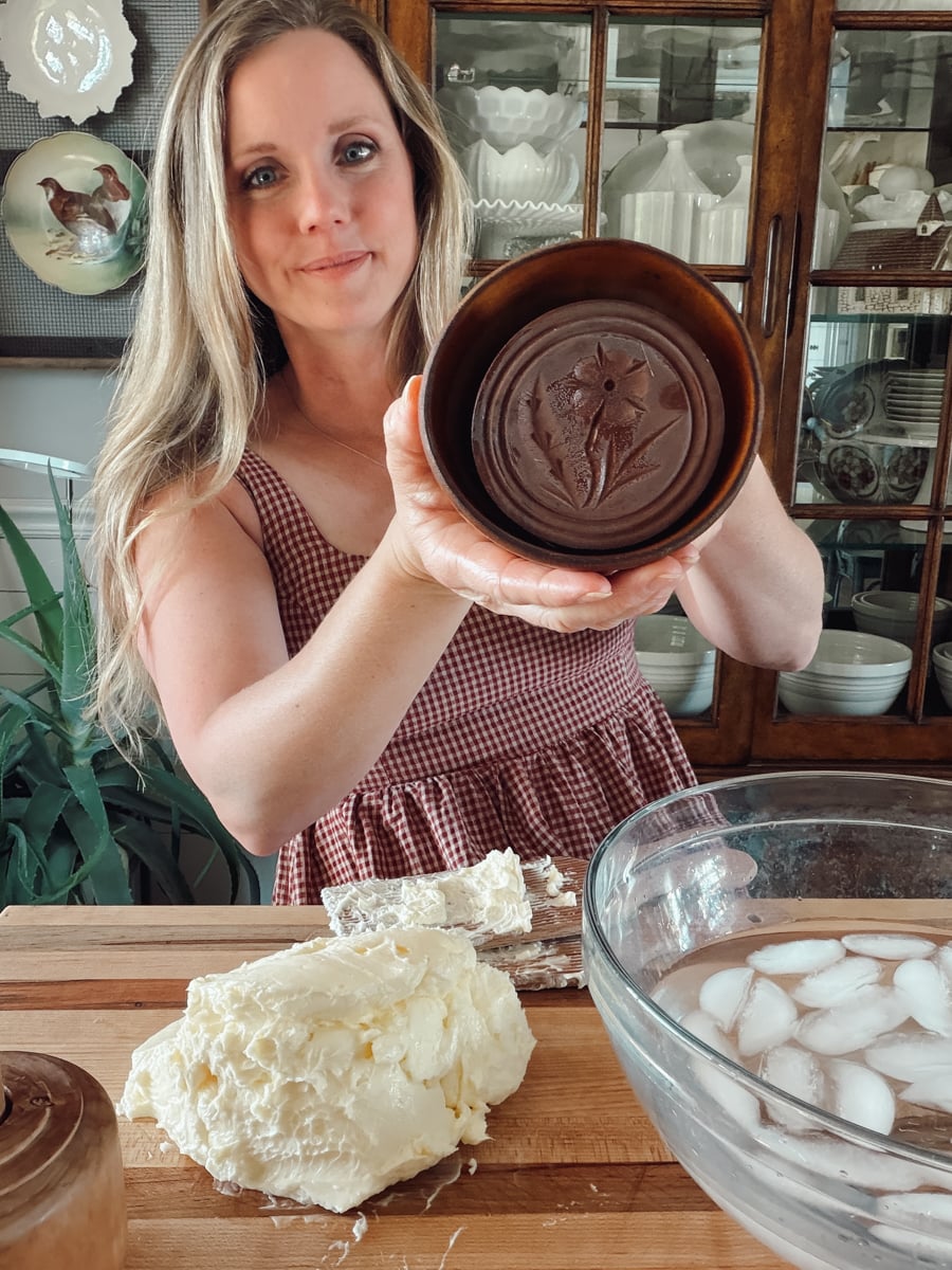 Woman holding the carved wooden stamp inside an antique butter mold before filling it with butter.