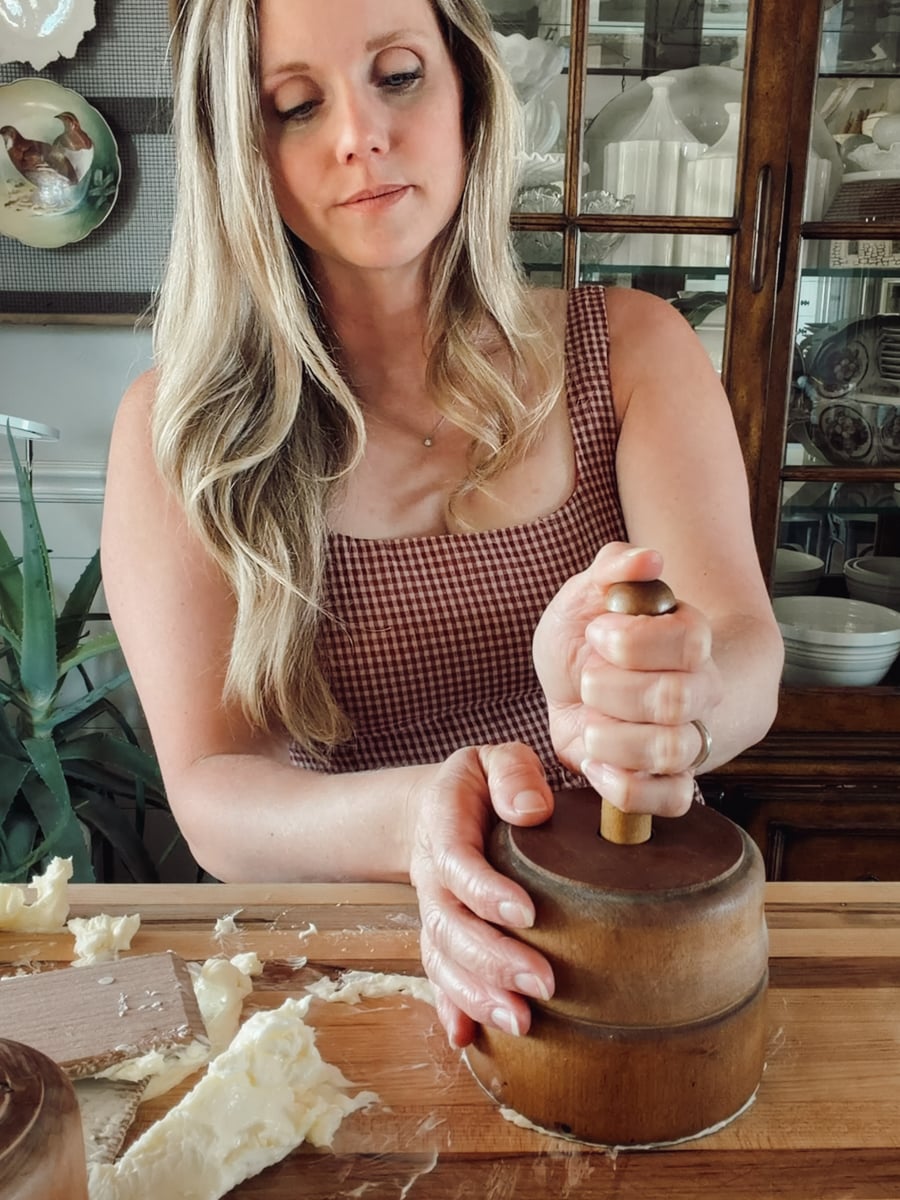 Pressing the wooden plunger into an antique butter mold filled with homemade butter